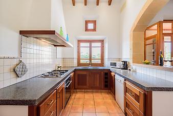 Finca Na Banya: Die Küche ist gut ausgestattet. Links erkennt man den Elektroherd mit Gaskochplatten, rechts die Geschirrspülmaschine, unter dem Fenster die Doppelspüle. Reichlich Kochgeschirr ist vorhanden.